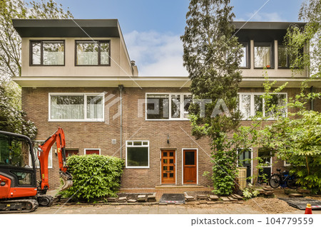 a house under construction with an exorm truck parked in the driveway and two windows on one side, surrounded by trees 104779559