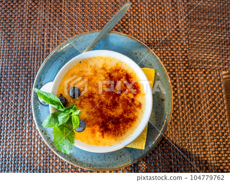 portion of creme brulee on saucer on table 104779762