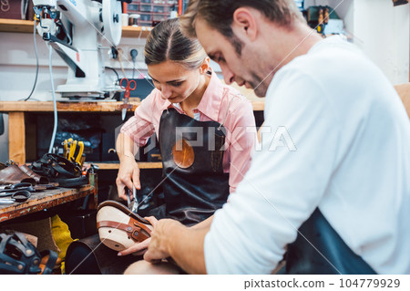 Two cobblers working together in the workshop 104779929