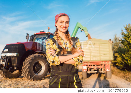 Proud famer standing in front of agricultural machinery 104779930