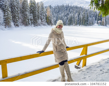 Woman in white clothes enjoying frozen lake Synevyr 104781152