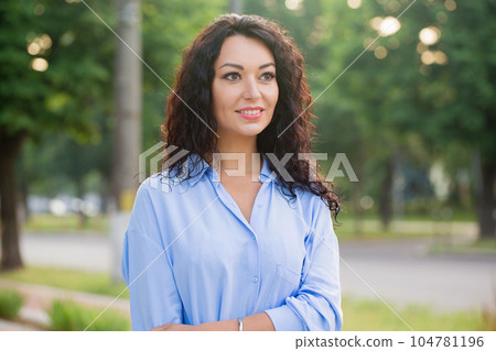 A beautiful smiling business woman in a blue shirt is walking down the alley in the city 104781196