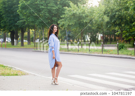A beautiful business woman in a blue long shirt crosses the road 104781197