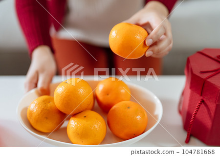 Asian Woman holding mandarin oranges with red gift box thankful present Lunar New Year. Chinese traditional holiday. Lunar new year culture. Asian Woman holding mandarin oranges with red gift box thankful present Lunar New Year. Chinese traditional holiday. Lunar new year culture. 104781668