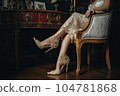 a woman sitting on a chair with her legs crossed and wearing high heeled shoes in the image is taken from behind 104781868