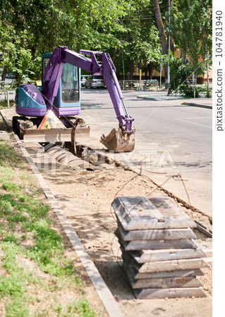 Big jackhammer drill drilling road.Heavy machinery crushing asphalt for stormwater drain repair. excavator tracks in the water. repair and expansion of a road 104781940