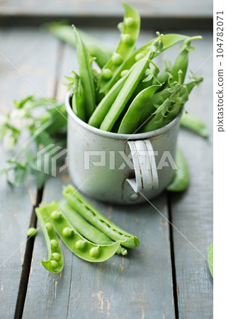 fresh green peas in a metal cup on a rustic background fresh green peas in a metal cup on a rustic background 104782071
