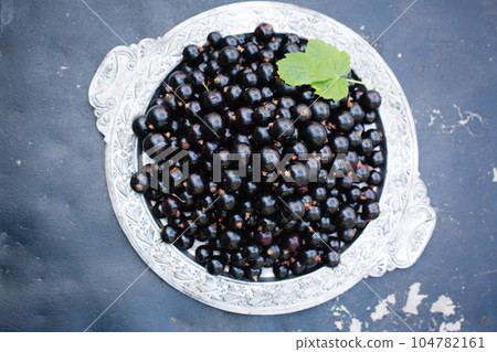 black currants in a vintage tray on a wooden background 104782161
