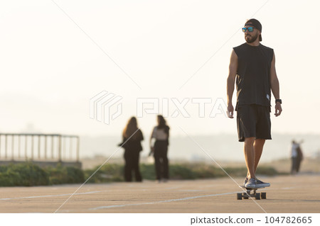 A man rides a skateboard in the early evening A man rides a skateboard in the early evening 104782665