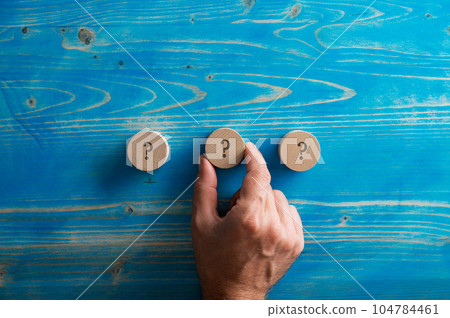 Three wooden cut circles with a question mark on each of them 104784461