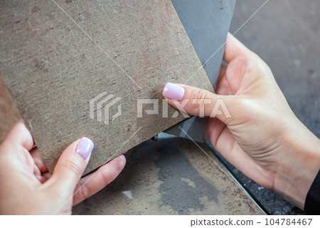 Samples of natural stone for floor production. The process of choosing the material for flooring. Samples of stone in hands close-up. 104784467