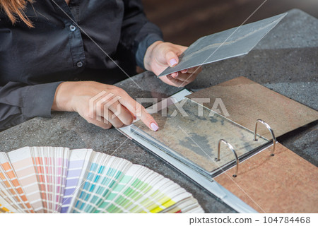 The choice of natural stone for interior decoration. A woman architect selects a shade of stone from samples close-up. The concept of renovation in the interior. 104784468