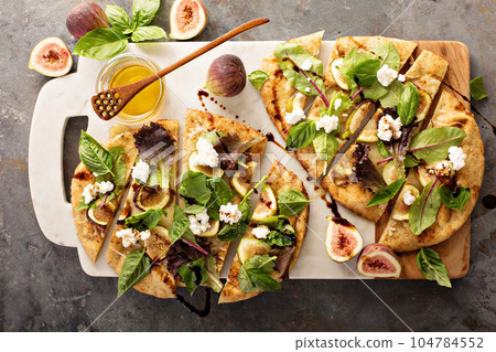 Flatbread pizza with figs, cheese and salad leaves Flatbread pizza with figs, cheese and salad leaves 104784552