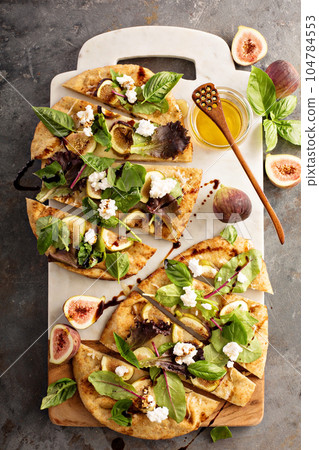 Flatbread pizza with figs, cheese and salad leaves Flatbread pizza with figs, cheese and salad leaves 104784553