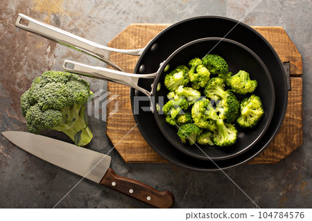 Steamed or stewed broccoli in a skillet 104784576
