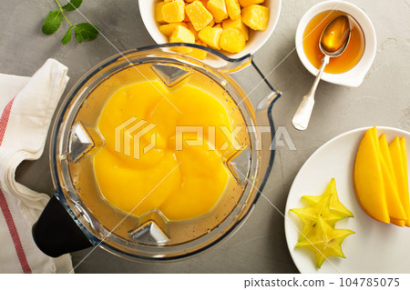 Making smoothie with frozen mango 104785075