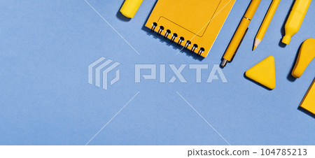 Assorted office and school yellow stationery on lilac blue. copy space for back to school or education craft office work concept. Bright Yellow rocket. Achievement and success. Top view Assorted office and school yellow stationery on lilac blue. copy space for back to school or education craft office work concept. Bright Yellow rocket. Achievement and success. Top view 104785213