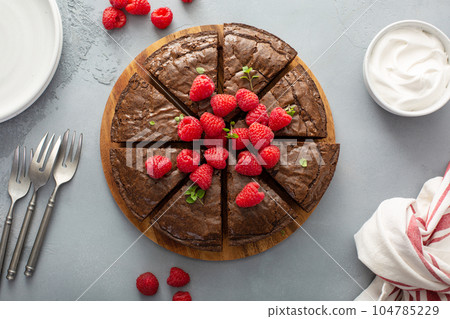 Brownie cake topped with fresh raspberries served with whipped cream 104785229