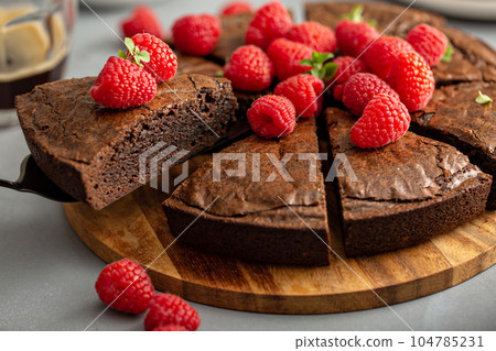 Brownie cake topped with fresh raspberries served with whipped cream 104785231