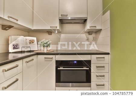 a kitchen with white cupboards and black counter tops on the wall above it is an oven in the corner 104785779