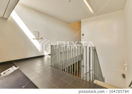 an empty room with stairs leading up to the second floor and light coming in through the window on the right side an empty room with stairs leading up to the second floor and light coming in through the window on the right side 104785784
