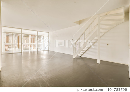 an empty living room with stairs leading up to the second floor and glass doors that lead out onto the balcony 104785796