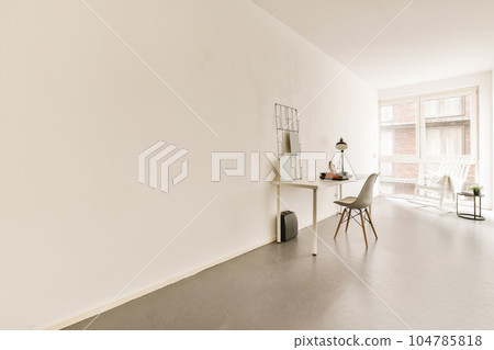 an empty living room with white walls and wood flooring, there is a small dining table in the corner an empty living room with white walls and wood flooring, there is a small dining table in the corner 104785818