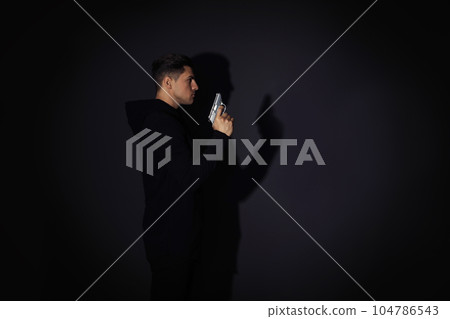Professional killer with gun on black background. Space for text 104786543
