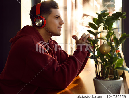 Man listening to audiobook at table in cafe Man listening to audiobook at table in cafe 104786559