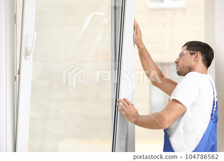 Construction worker repairing plastic window with screwdriver indoors 104786562