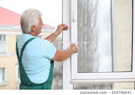 Mature construction worker repairing plastic window indoors 104786641