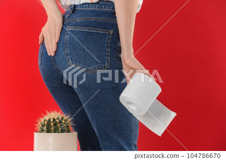 Woman with toilet paper sitting down on cactus against red background, closeup. Hemorrhoid concept Woman with toilet paper sitting down on cactus against red background, closeup. Hemorrhoid concept 104786670