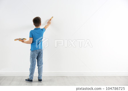Little child painting on white wall indoors. Space for text 104786725