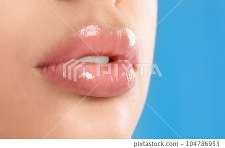 Young woman with beautiful full lips on light blue background, closeup 104786953