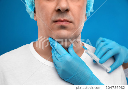 Mature man with double chin receiving injection on blue background, closeup 104786982