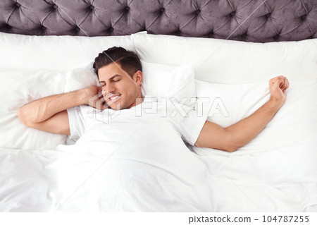 Man awakening in bed at home, top view. Lazy morning 104787255