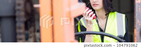 Young asian woman is foreman using radio for communication while driving forklift. Young asian woman is foreman using radio for communication while driving forklift. 104791062