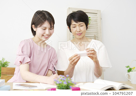 Daughter studying with her mother at home Daughter studying with her mother at home 104791207