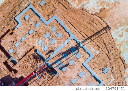 Builder pouring wet concrete to house foundation with using of concrete pump Builder pouring wet concrete to house foundation with using of concrete pump 104791451