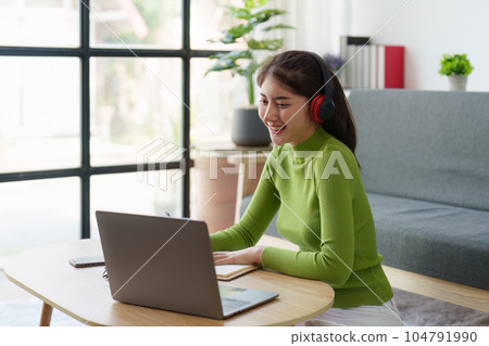 Young asian relaxed smiling pretty woman relaxing with laptop at home. Female feeling joy enjoying with mobile phone on cozy couch Young asian relaxed smiling pretty woman relaxing with laptop at home. Female feeling joy enjoying with mobile phone on cozy couch 104791990