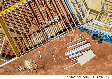Construction site during framework new residential house with wooden framing along walls made of planks. Construction site during framework new residential house with wooden framing along walls made of planks. 104792147