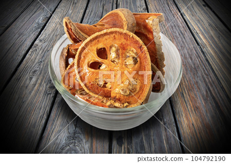 Sliced bael in a glass bowl is placed on wooden table. 104792190