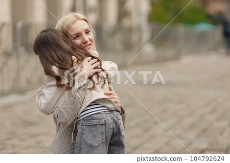 Little girl embracing her mother. Woman has painted flag of Ukraine in blue and yellow colours on her cheek. Woman and girl supporting Ukraine against war. Little girl embracing her mother. Woman has painted flag of Ukraine in blue and yellow colours on her cheek. Woman and girl supporting Ukraine against war. 104792624