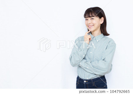 A woman in her thirties thinking with a smile in front of a white background 104792665