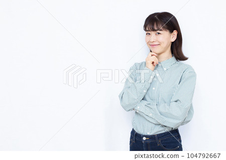 A woman in her thirties thinking with a smile in front of a white background 104792667