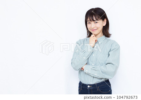 A woman in her thirties thinking with a smile in front of a white background A woman in her thirties thinking with a smile in front of a white background 104792673