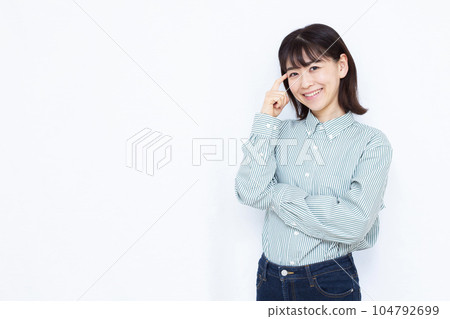 A woman in her thirties thinking with a smile in front of a white background 104792699
