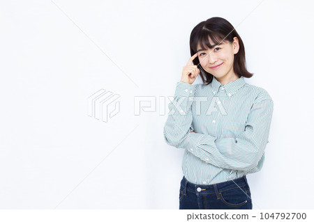 A woman in her thirties thinking with a smile in front of a white background 104792700