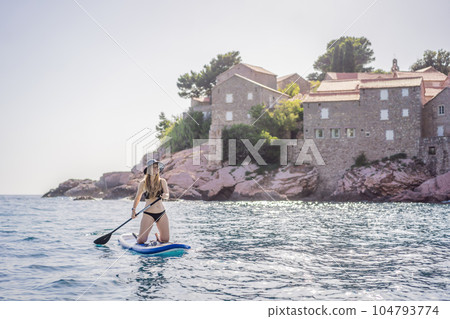 Young women Having Fun Stand Up Paddling in blue water sea near st stefan island in Montenegro. SUP 104793774