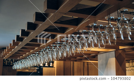 Wine glasses hang above bar counter 104793802